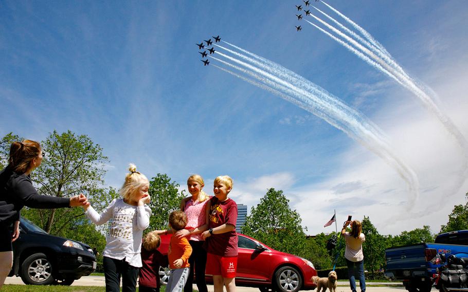 The Ferry family, from Chantilly, Va., who were in the middle of taking a family photograph, are surprised by a second fly over by the Blue Angels and Thunderbirds, in a "salute to frontline COVID-19 responders," as seen near the U.S. Marine Corps War Memorial that depicts a flag raising over Iwo Jima, in Arlington, Va., Saturday, May 2, 2020. 
