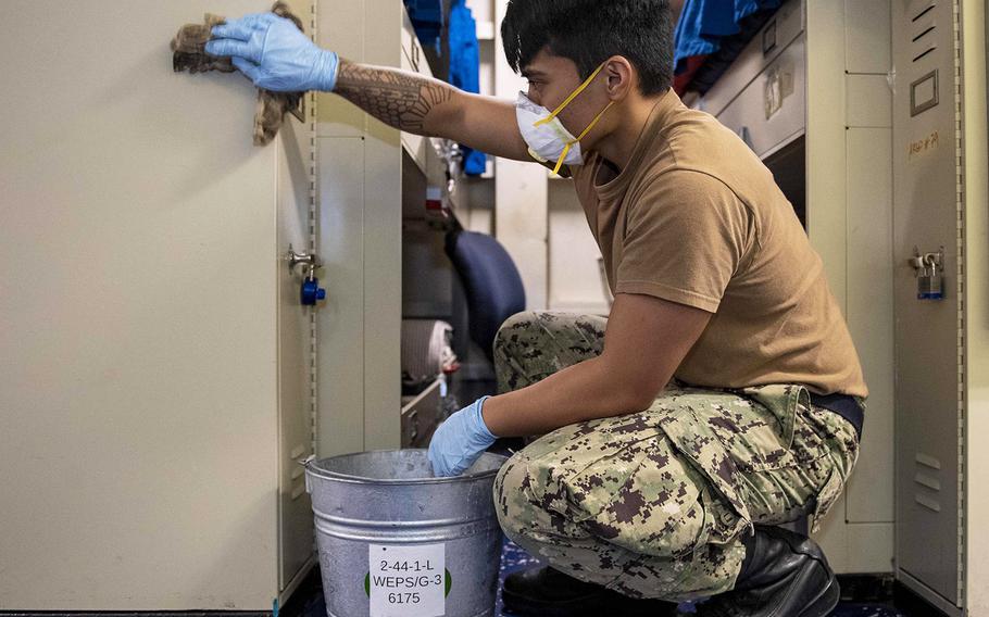 In an April 27, 2020 photo, U.S. Navy Aviation Ordnanceman Airman Ernesto Maduro sanitizes berthing aboard the aircraft carrier USS Theodore Roosevelt during morning "bleach-a-palooza," a term used by the crew for multiple sanitizing routines throughout the day requiring the participation of all-hands.