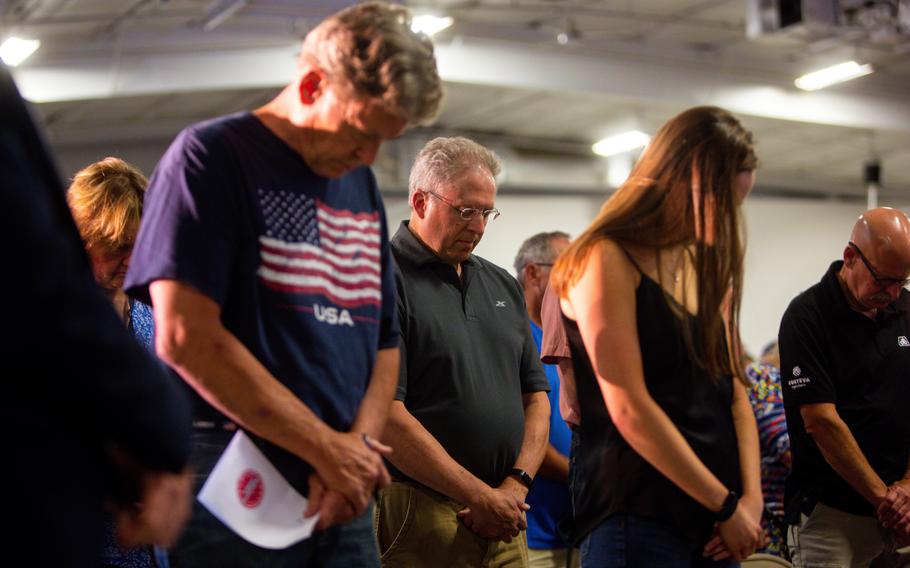 People bow their heads as they are led in prayer before a speech by Florida Gov. Ron DeSantis (R) on May 31, 2023, at Hawkeye Downs Speedway and Expo Center, in Cedar Rapids, Iowa. 