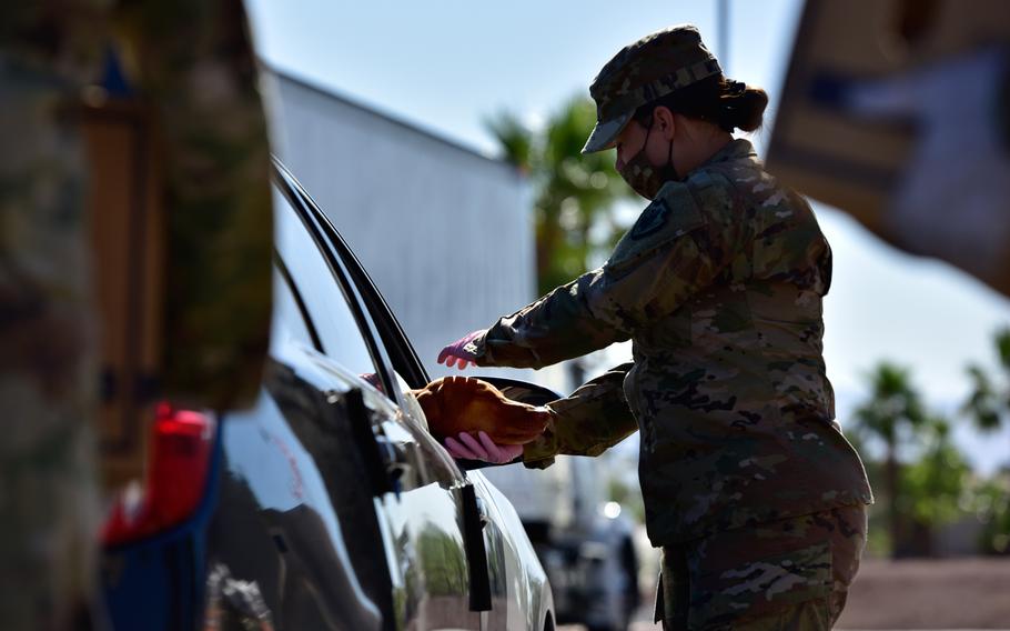 U.S. Army Sgt. Mary Motter, with the 250th Expeditionary Military Intelligence Battalion, California Army National Guard, pets a family's dog, Stella, during a drive-thru food distribution event hosted by FIND Food Bank in La Quinta, California, May 20, 2020. 