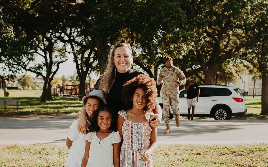 Lt. Col. Simon McKenzie gets ready to surprise his family during a photo shoot as wife Kristin McKenzie poses for photos with their kids (left to right) Grey, Lawton and Blake.