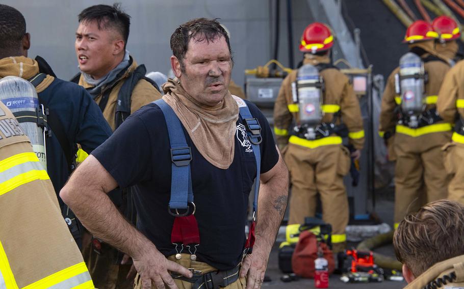 Firefighter John Farrell, from Federal Fire Station 13 at Naval Amphibious Base Coronado, emerges from USS Bonhomme Richard.
