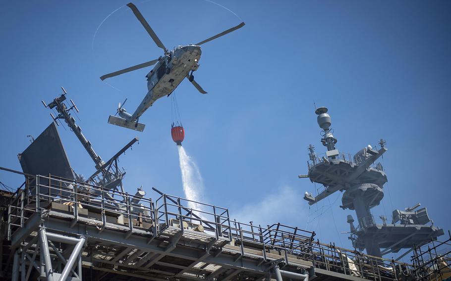 An MH-60S Sea Hawk helicopter combats a fire aboard the USS Bonhomme Richard on July 14, 2020. On the morning of July 12, a fire was called away aboard the ship while it was moored pier side at Naval Base San Diego. Base and shipboard firefighters responded to the fire.