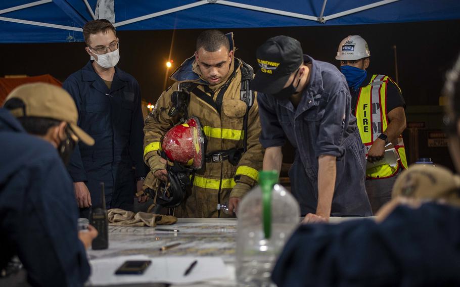 Sailors discuss ongoing firefighting operations aboard the amphibious assault ship USS Bonhomme Richard at Naval Base San Diego on July 14, 2020.