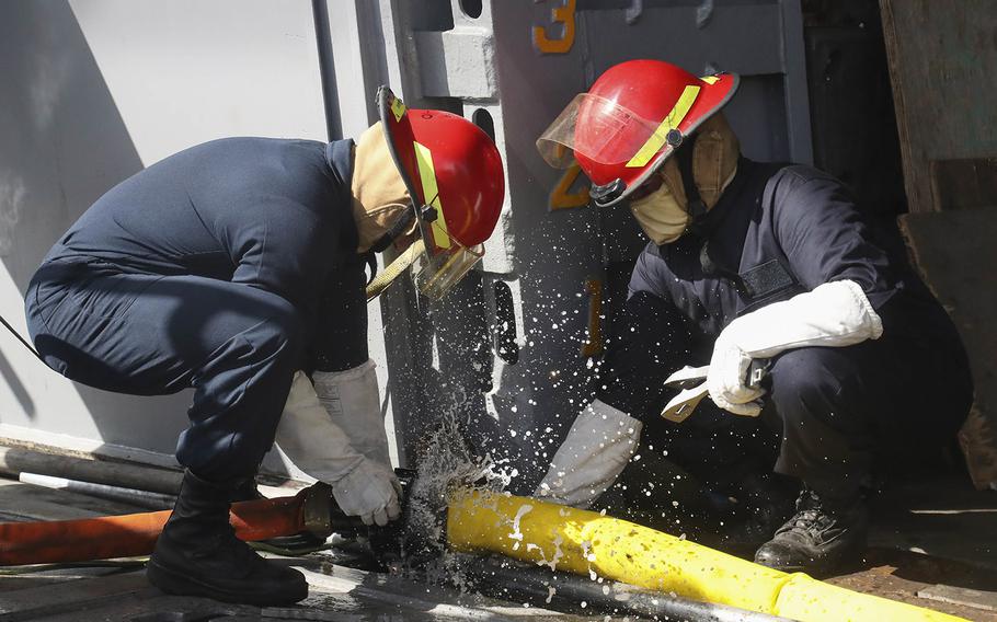 Sailors disconnect hoses in the well deck of the USS Bonhomme Richard in support of firefighting efforts on July 14, 2020. 