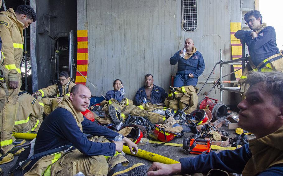 Sailors rest after battling a fire aboard the amphibious assault ship USS Bonhomme Richard on July 14, 2020. 