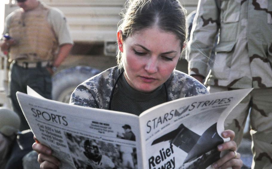First Lt. Tracy Tyson from Seattle, Wash., assigned to the 5th Brigade 2nd Infantry Division, reads Stars and Stripes at Kandahar Airfield, Afghanistan, while waiting for a flight to Forward Observation Base Wolverine in 2009.