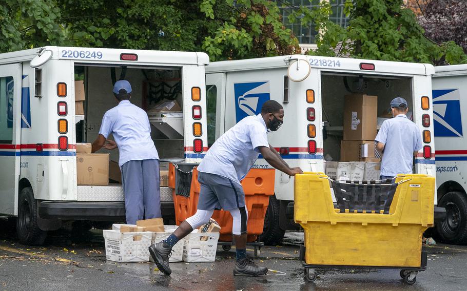 Letter carriers load mail trucks for deliveries at a U.S. Postal Service facility in McLean, Va., on July 31, 2020. 