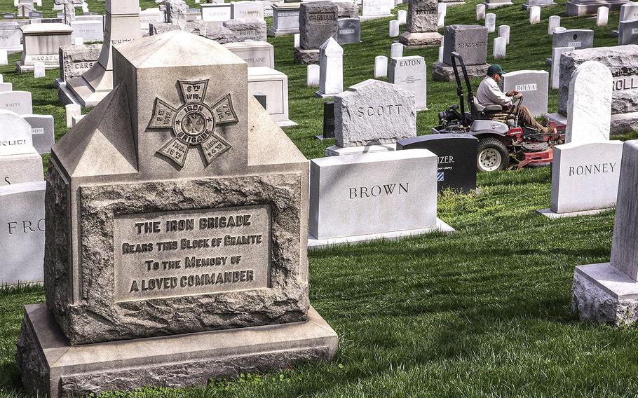 An Arlington National Cemetery worker mows the grass on gravesites in 2017.