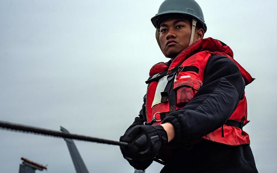 Seaman Isaiah Peralta holds the phone and distance line on the flight deck of the aircraft carrier USS Theodore Roosevelt during a replenishment-at-sea Dec. 3, 2019.