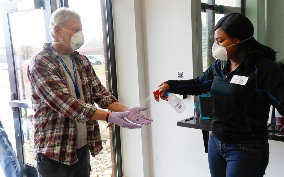 Sgt. Monica Miggins, right, a soldier with the 1158th Transportation Company out of Beloit, Wis., sanitizes a voter's hands before he enters a polling station in Fitchburg, Wis., on April 7, 2020. More than 2,400 Citizen Soldiers and Airmen were mobilized to state active duty to assist as poll workers in the stateâ€™s election. Wisconsin National Guard Photo by Spc. Emma Anderson