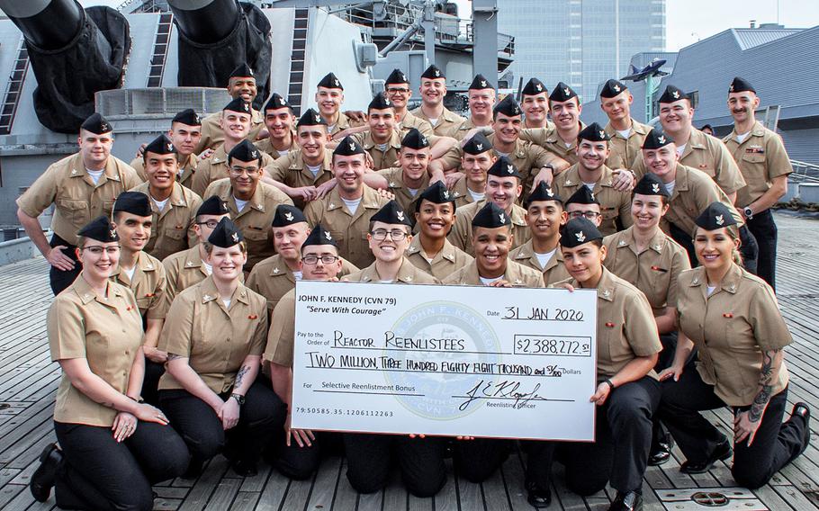 In a January, 2020 photo, Pre-Commissioning Unit John F. Kennedy Reactor Department sailors stand with their reenlistment check onboard the Battleship USS Wisconsin after their group reenlistment that earned them Selective Reenlistment Bonuses.