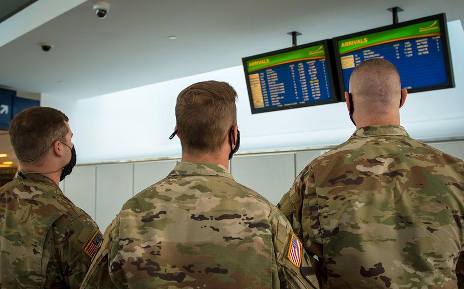 In an Oct. 23, 2020 photo, Army Spc. Kevin Hamilton, Sgt. Benjamin Zawacki and Staff Sgt. James Kociencki, assigned to 105th Military Police Company, Buffalo, N.Y., check the arrival boards at Buffalo-Niagara International Airport.