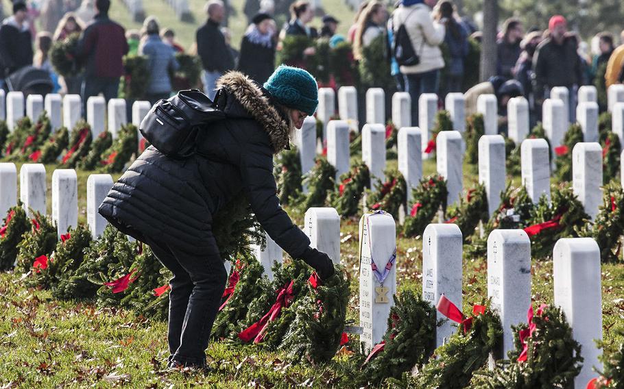 A volunteer places a wreath during Wreaths Across America at Arlington National Cemetery, Dec. 13, 2014.