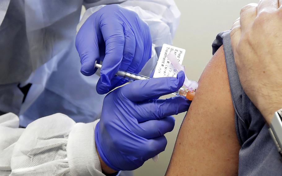 In this March 16, 2020 file photo, a subject receives a shot in the first-stage safety study clinical trial of a potential vaccine by Moderna for COVID-19, the disease caused by the new coronavirus, at the Kaiser Permanente Washington Health Research Institute in Seattle. 