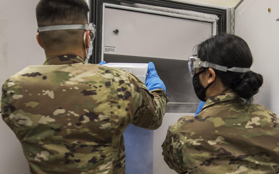 Airman 1st Class Raymond De Jesus, 59th Medical Wing medical logistics technician, and Staff Sgt. Romina Guridi, 59 MDW medical logistics warehouse supervisor, place the San Antonio Military Health System's first cases of the Pfizer COVID-19 vaccine into a subzero freezer, Dec. 14, 2020, at Wilford Hall Ambulatory Surgical Center, Joint Base San Antonio-Lackland, Texas.