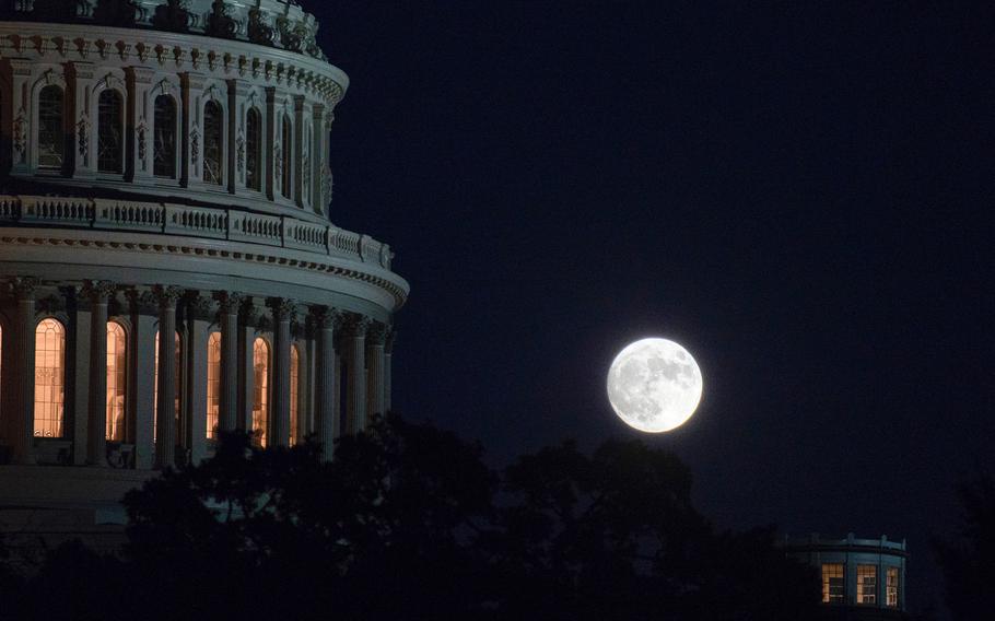 A full moon rises over the nation's capitol on Oct. 30, 2020, with the U.S. Capitol in the foreground. Government funding lapses at midnight on Friday, Dec. 18, 2020, and a partial, low-impact shutdown would ensue if Congress fails to pass a stopgap spending bill before then. 