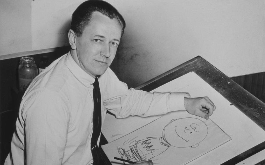 Charles M. Schulz sits at a drafting table with a drawing of Charlie Brown in 1956. Schulz, who served in the Army during World War II, created the comic strip Peanuts, which featured the characters Charlie Brown and Snoopy, among others.