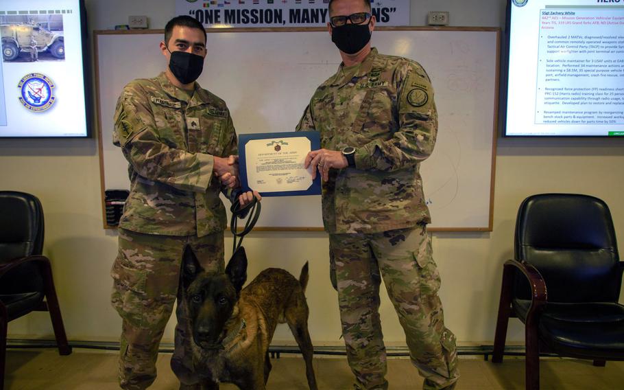 Brig. Gen. Larry Q. Burris Jr. presents Sgt. Michael Ramirez and Fritz, his military working dog, with Army Commendation Medals in Dec. 2020 for discovering a cache of unexploded bombs in Syria.
