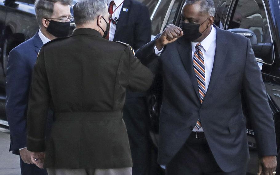 Defense Secretary Lloyd Austin gives an elbow bump to Army Gen. Mark Milley, chairman of the Joint Chiefs of Staff, upon his arrival at the Pentagon Jan. 22, 2021. With then is Acting Defense Secretary David Norquist. Austin was sworn in as the 28th defense secretary shortly afterward.