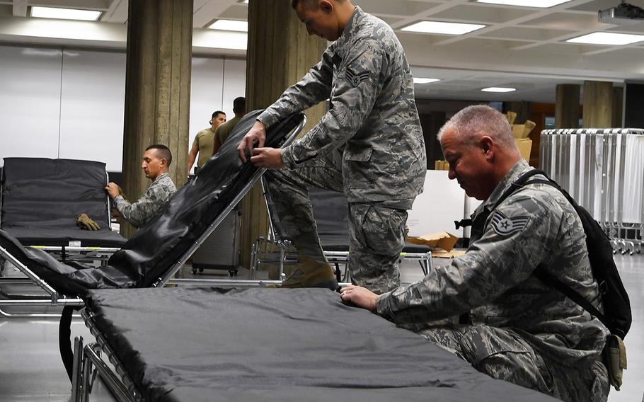 In an April 4, 2020 photo, airmen from the California Air National Guard's 146th Airlift Wing assemble cots at the Redding Civic Auditorium in Redding, California. This federal medical station (FMS) location was to have 100 general-use beds for patients from local hospitals experiencing overflow due to the coronavirus crisis.