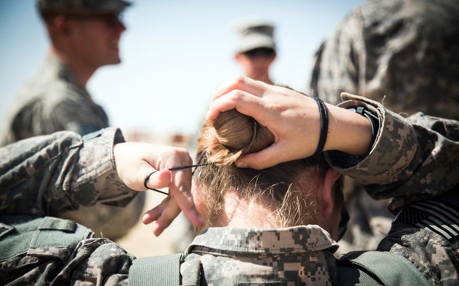 Spc. Nina Bray fixes her hair bun before putting on her body armor at a M203/M320 40 mm grenade launcher qualification range at Camp Buehring, Kuwait, March 17, 2014. 