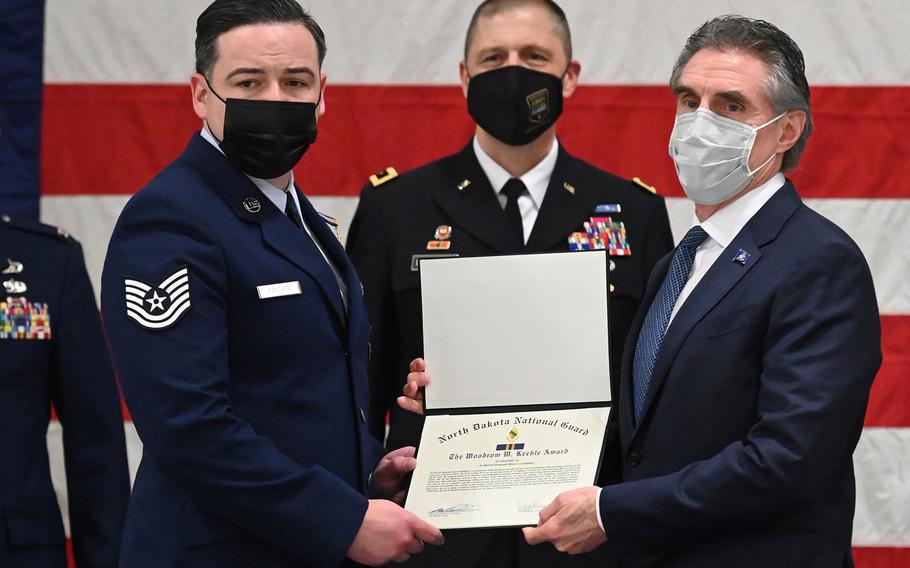 Gov. Doug Burgum, right, presents the Woodrow W. Keeble Award to Tech. Sgt. Ryan Fontaine of Minot Air Force Base's 219th Security Forces Squadron as Maj. Gen. Al Dohrmann looks on at the North Dakota Air National Guard Base, Fargo, N.D., March 6, 2021.
