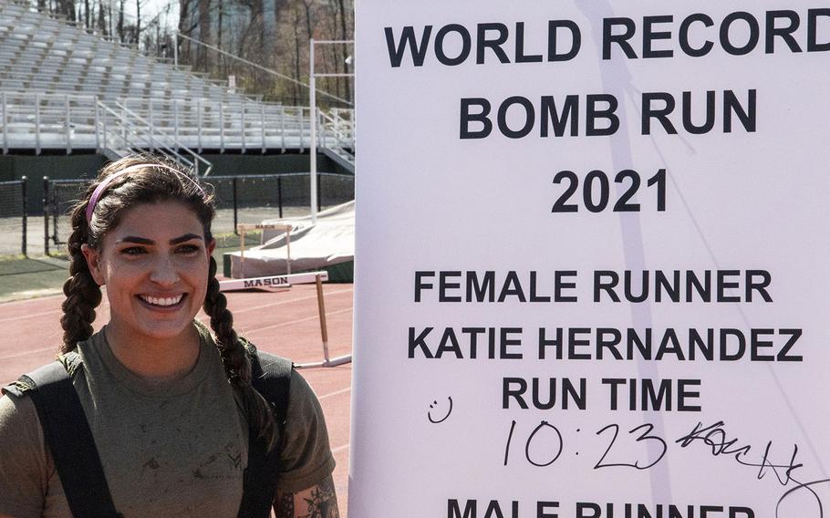 Army Capt. Katie Hernandez poses next to the finish-line banner after setting a world women's record for a mile run in a bomb disposal suit, Saturday, April 3, 2021, at George Mason University in Fairfax, Va.