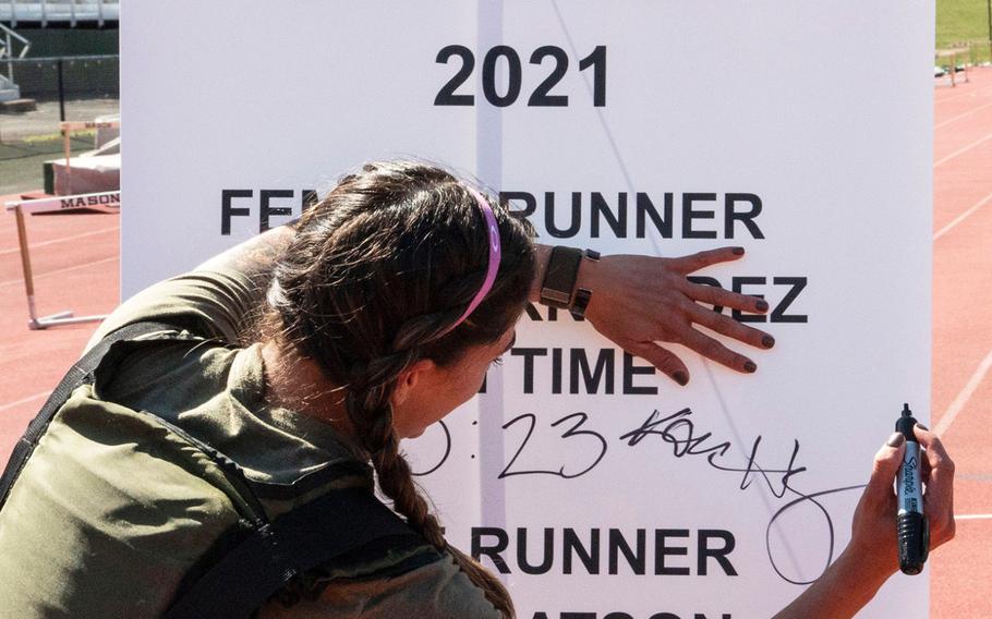 Army Capt. Katie Hernandez signs the finish-line banner after setting a world women's record for a mile run in a bomb disposal suit, Saturday, April 3, 2021, at George Mason University in Fairfax, Va.