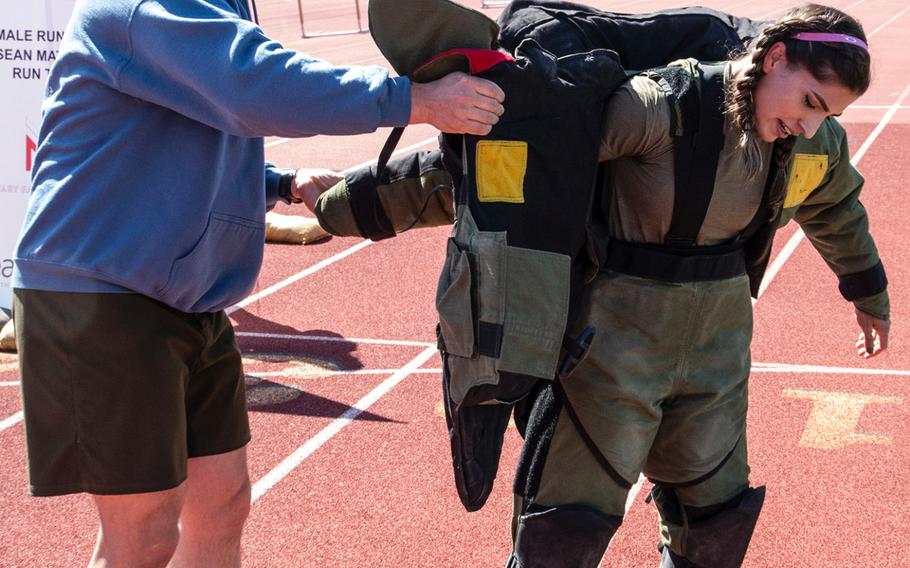 Army 1st Sgt. John Myers helps Capt. Katie Hernandez out of a bomb disposal suit after she set a world women's record for a mile run in the protective gear, Saturday, April 3, 2021, at George Mason University in Fairfax, Va.