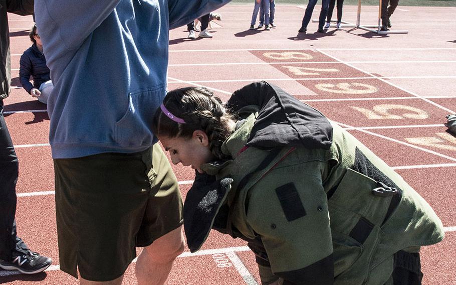 Army 1st Sgt. John Myers helps Capt. Katie Hernandez out of a bomb disposal suit after she set a world women's record for a mile run in the protective gear, Saturday, April 3, 2021, at George Mason University in Fairfax, Va.