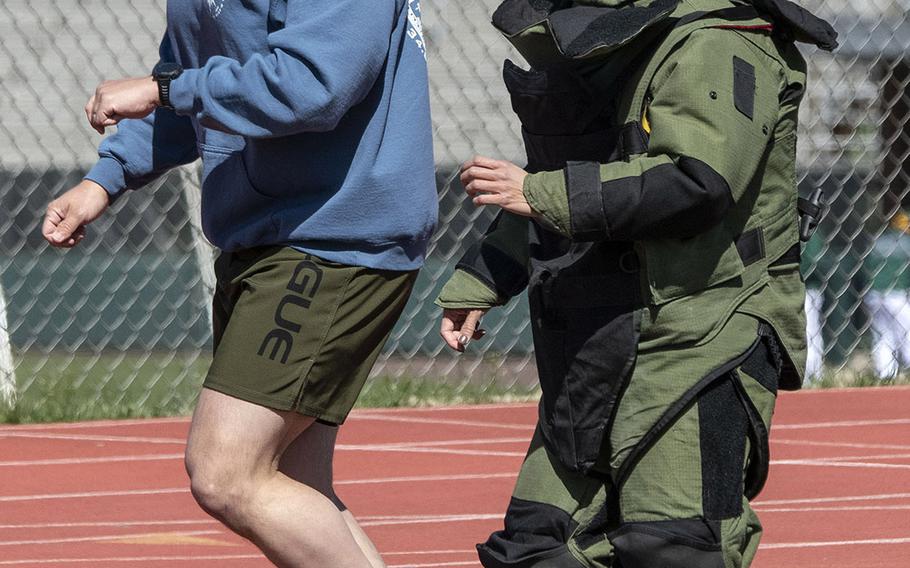 Paced by by Army 1st Sgt. John Myers, Capt. Katie Hernandez tries for the world women's record for a mile run in a bomb disposal suit, Saturday, April 3, 2021, at George Mason University in Fairfax, Va.