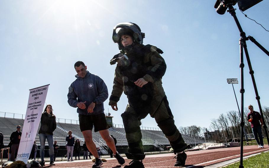 Paced by by Army 1st Sgt. John Myers, Army Capt. Katie Hernandez starts her quest for the world women's record for a mile run in a bomb disposal suit, Saturday, April 3, 2021, at George Mason University in Fairfax, Va.