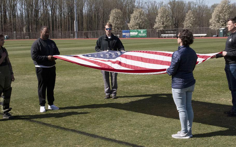 Army Capt. Katie Hernandez, left, stands for the playing of the national anthem before her attempt at a world women's record for a mile run in a bomb disposal suit, Saturday, April 3, 2021, at George Mason University in Fairfax, Va.