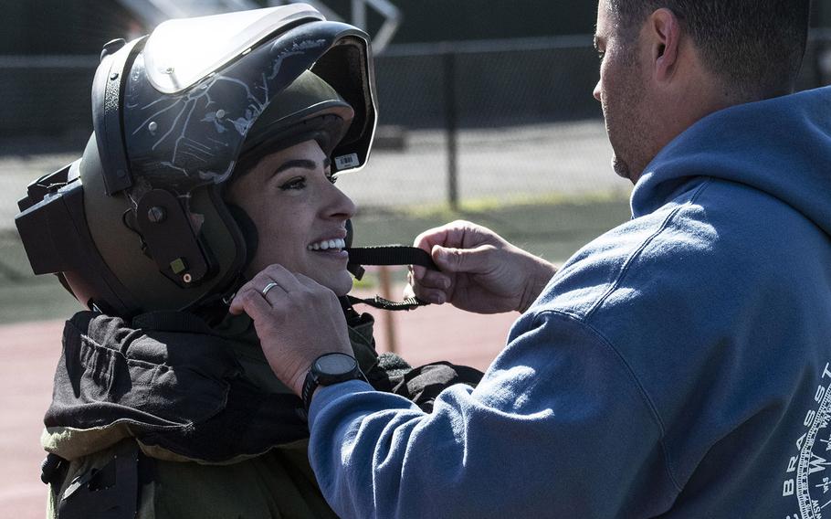 Army Capt. Katie Hernandez is helped into a bomb disposal suit by 1st Sgt. John Myers before her attempt at a world women's record for a mile run in the protective gear, Saturday, April 3, 2021, at George Mason University in Fairfax, Va.