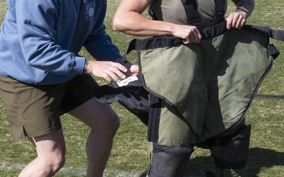 Army Capt. Katie Hernandez is helped into a bomb disposal suit by 1st Sgt. John Myers before her attempt at a world women's record for a mile run in the protective gear, Saturday, April 3, 2021, at George Mason University in Fairfax, Va.