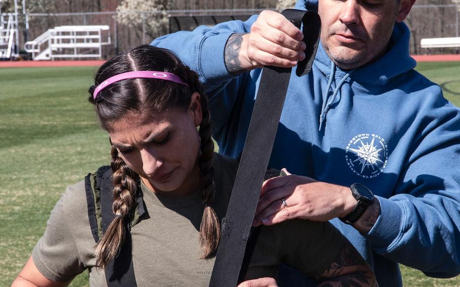 Army Capt. Katie Hernandez is helped into a bomb disposal suit by 1st Sgt. John Myers before her attempt at a world women's record for a mile run in the protective gear, Saturday, April 3, 2021, at George Mason University in Fairfax, Va.