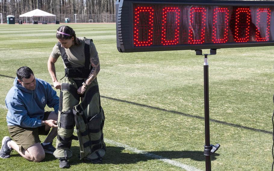 Army Capt. Katie Hernandez is helped into a bomb disposal suit by 1st Sgt. John Myers before her attempt at a world women's record for a mile run in the protective gear, Saturday, April 3, 2021, at George Mason University in Fairfax, Va.