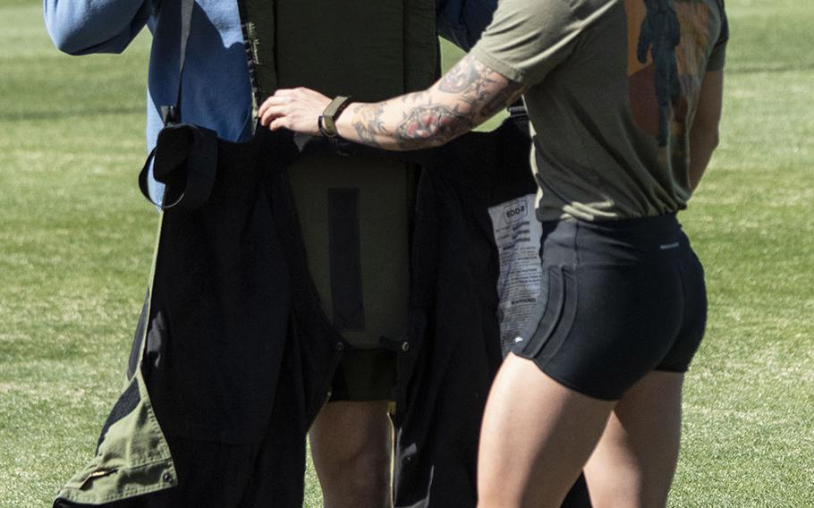 Army Capt. Katie Hernandez is helped into a bomb disposal suit by 1st Sgt. John Myers before her attempt at a world women's record for a mile run in the protective gear, Saturday, April 3, 2021, at George Mason University in Fairfax, Va.