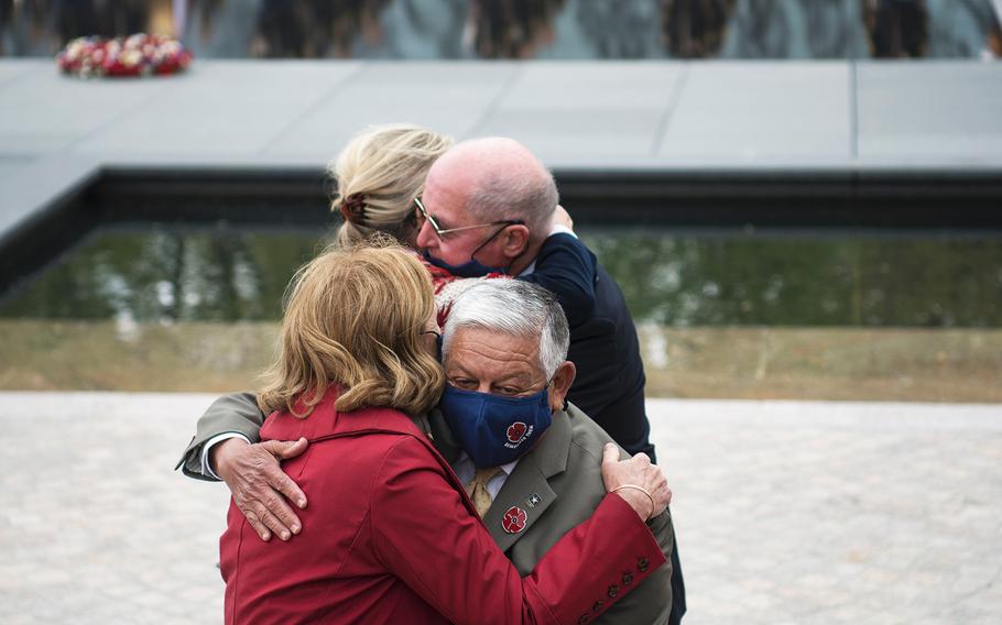 Dignitaries who were involved in promoting the new World War I Memorial hug each other at the conclusion of a dedication ceremony for the site on Friday, April 16, 2021, in Washington, D.C.