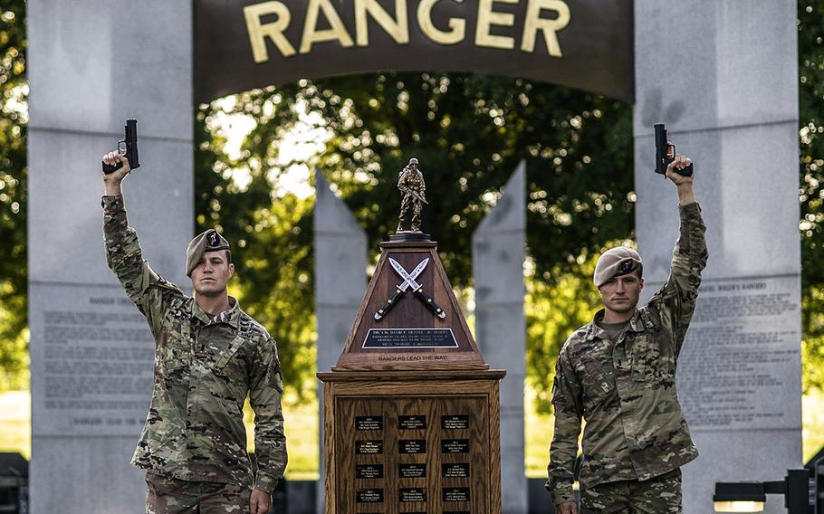 Army 1st. Lt. Vince Paikowski and 1st Lt. Alastair Keys, assigned to the 75th Ranger Regiment, raise pistols in the air at the Ranger Memorial on Fort Benning, Ga., April 19, 2021.