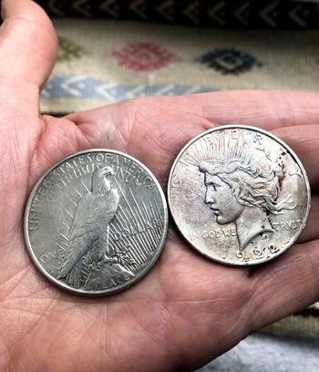 The back and front of two silver dollar peace coins from 1922 and 1923. Peace coins are popular as the silver coin that newly commissioned officers give to the person who  salutes them for the first time.
