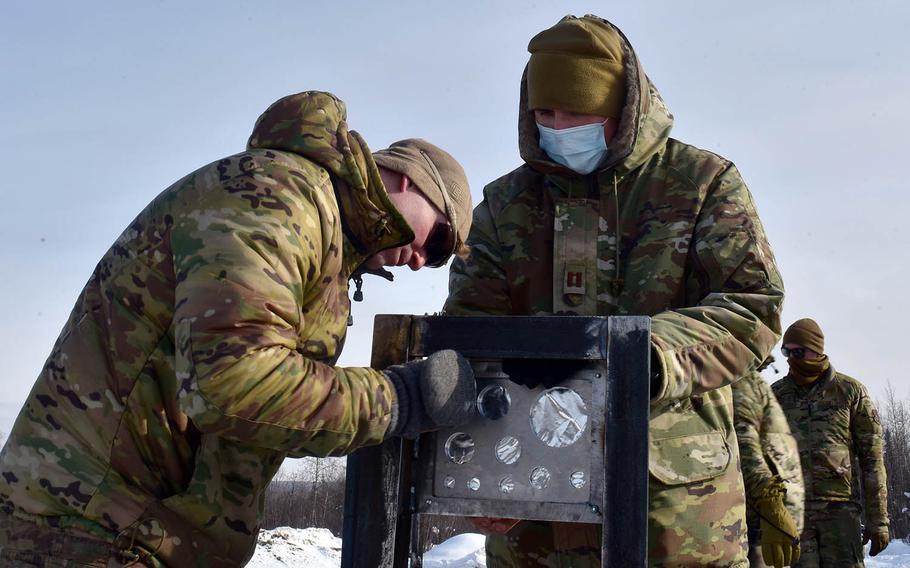 Airmen attach the metal plates of a bikini gauge used in testing snow barriers to mitigate shockwaves from detonations at Eielson Air Force Base, Alaska, March 18, 2021.