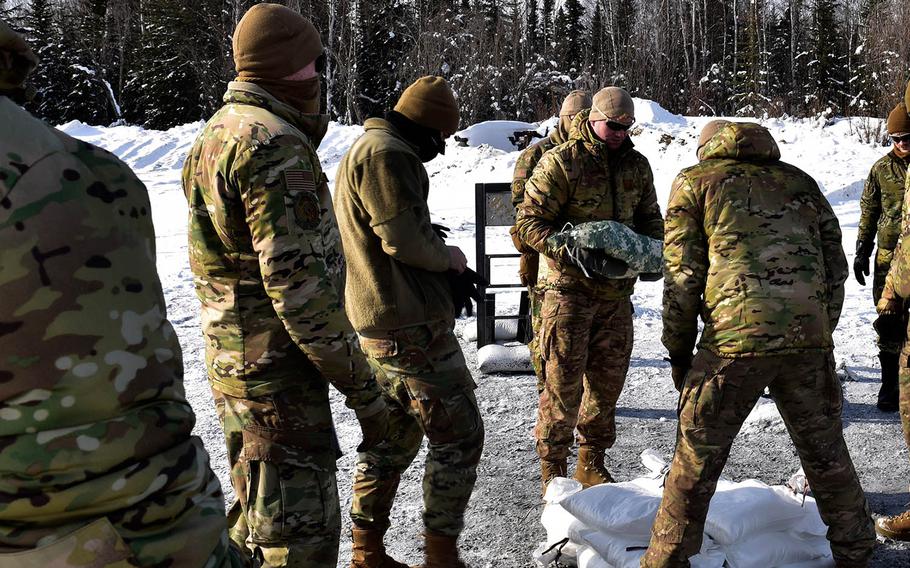 Airmen place snow-filled bags around an explosive charge during an experiment at Eielson Air Force Base, Alaska, March 18, 2021. 