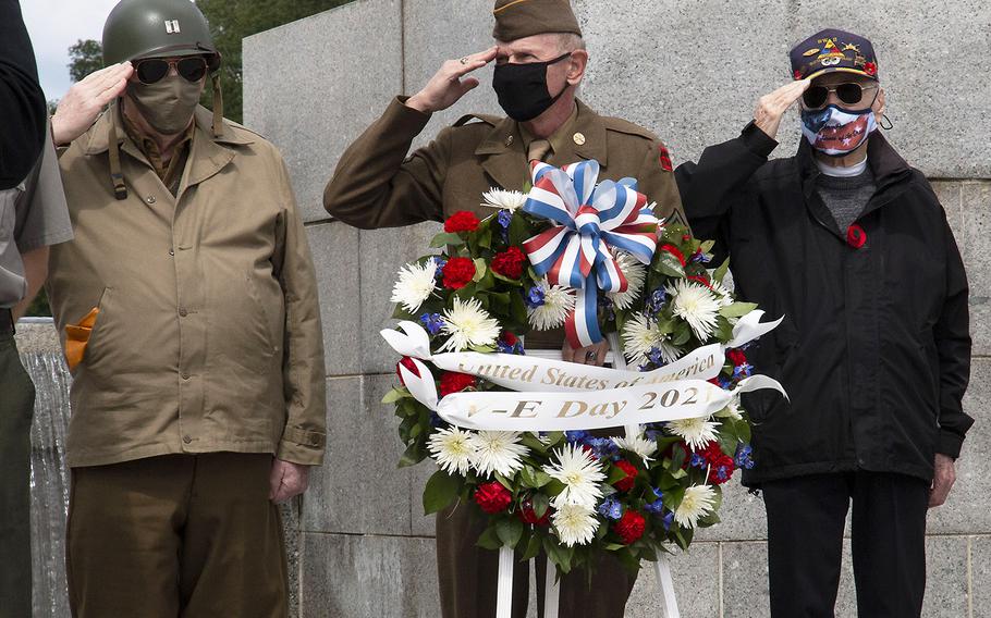 National Park Service volunteer and reenactor Patrick McCourt, Vietnam-era veteran Sidney O. Wade Jr. and World War II veteran Harry Martin, left to right, salute as the national anthem is played during a ceremony at the National World War II Memorial in Washington, D.C. on May 8, 2021, the anniversary of the end of the war in Europe.