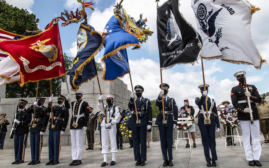 The Military District of Washington Armed Forces Color Guard battles the wind as the national anthem is played during a ceremony at the National World War II Memorial in Washington, D.C. on May 8, 2021, the anniversary of the end of the war in Europe.