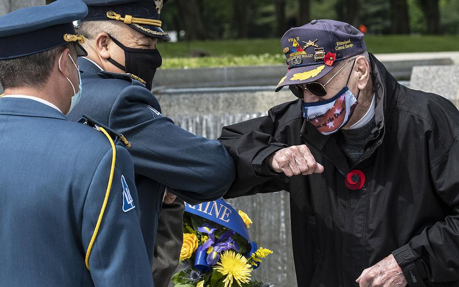 World War II veteran Harry Miller elbow-bumps Ukrainian Defense Attache Maj. Gen. Borys Krementskyi before a ceremony at the National World War II Memorial in Washington, D.C. on May 8, 2021, the 76th anniversary of the end of the war in Europe. Last year's planned 75th anniversary ceremonies were canceled due to the pandemic.