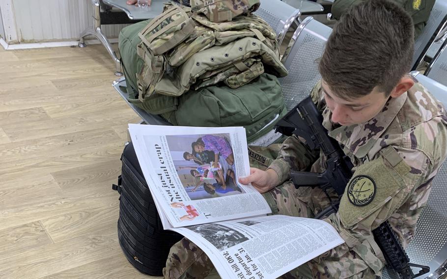 Spc. Angel Ruszkiewicz, 21, a combat camera specialist from Milwaukee, Wi., reads a Stars and Stripes at the passenger terminal on a coalition base in Erbil, Iraq, on Monday, Dec. 23, 2019, before a flight to Syria.

