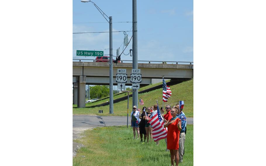 People gathered at the exit to Fort Hood as the body of Army Sgt. James G. Johnston is escorted Friday from a ceremony at the base to a local funeral home. The soldier, who died in Afghanistan on June 25, will be buried Monday.
