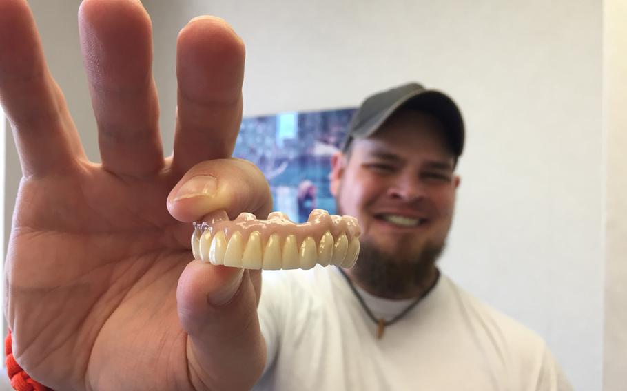 Dustin Kirby holds a new set of customized teeth, fashioned for him by a medical staff from Northwell Health. Kirby, a former Navy corpsman grievously wounded by a sniper's bullet in 2006, is scheduled to share his story of recovery at Side by Side, a Northwell-sponsored music event at  New York's Fleet Week 2019. 